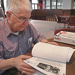 Con Marshall, Information Services Officer, flips through the proff of the Centennial History Book during interview Tuesday. — Photo by Ashley Swanson